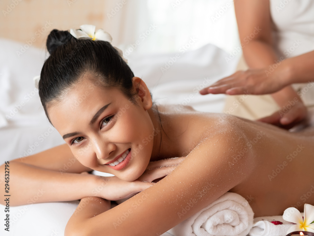 Obraz premium Beautiful young asian woman lying smile on the bed Getting a Salt Scrub Beauty Treatment in the Health Spa. Body Scrub. Select focus face women