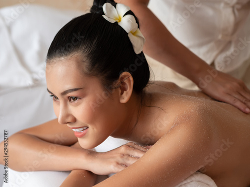 Beautiful young asian woman lying smile on the bed Getting a Salt Scrub Beauty Treatment in the Health Spa. Body Scrub. Select focus face women