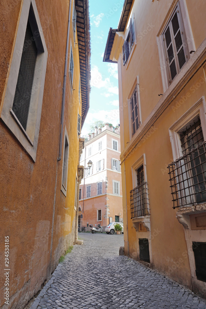 Empty narrow cobblestone street going among old houses with shabby yellow walls in the historical center of the city