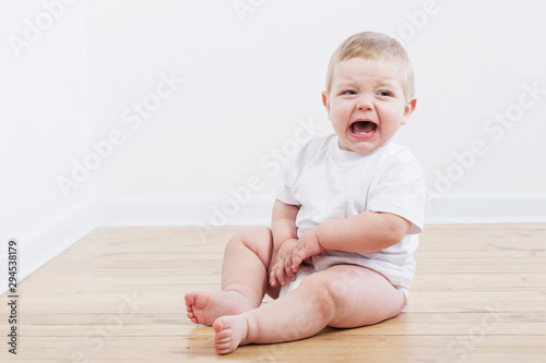 Photo baby crying sitting on wooden floor