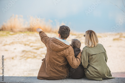 Tableau sur toile young beautiful family sitting at beach with view lake