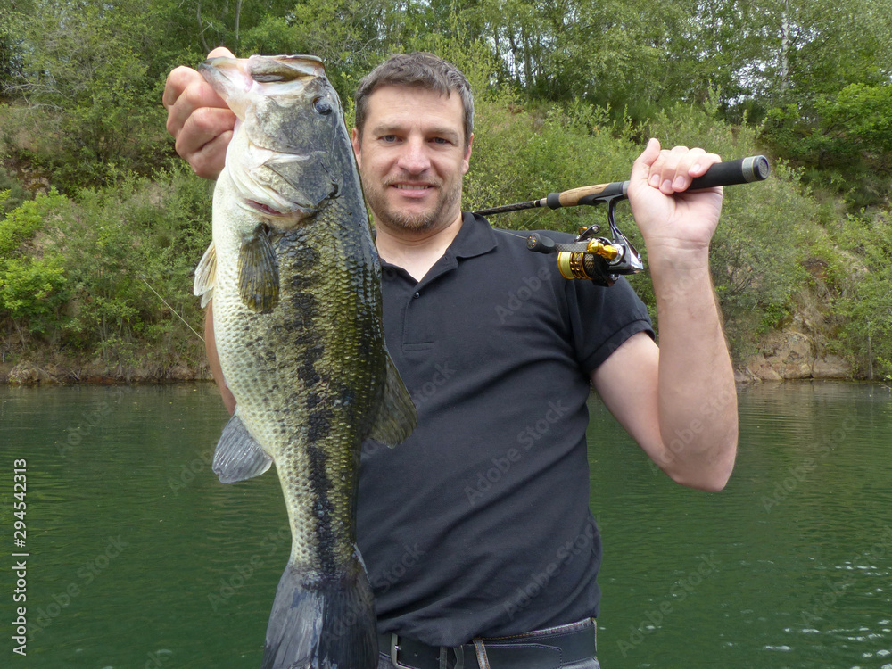Lucky fisherman holding a large bass fish. Freshwater fishing