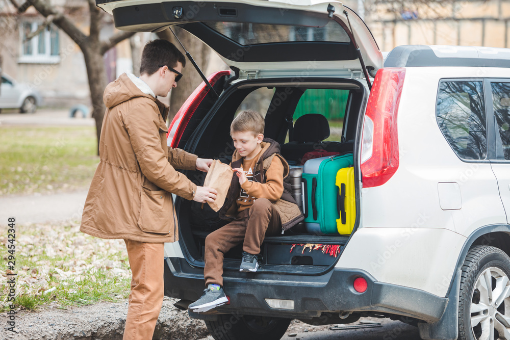 father with son packing bags to car trunk. car travel concept father with son packing bags to car trunk. car travel concept