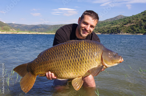 Carp fishing, man holding a big common carp. France