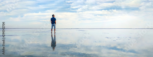 man in the water at sea. concept of a happy holiday and freedom. tourist looking at the horizon line. Beautiful panorama of the salt lake with the reflection of white clouds in the ode.