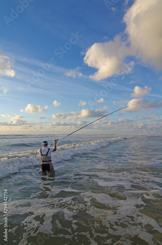 Sea fishing, surf fisherman into the waves cast the line