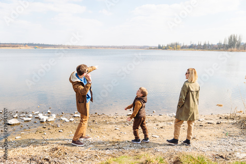 father teaching little son throw rocks in water