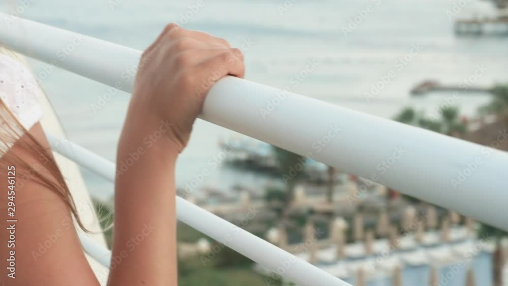 Female hand sliding on white handrail summer balcony with sea view. Close up teenager girl hands on railing outdoor terrace resort Female hand sliding on white handrail summer balcony with sea view. Close up teenager girl hands on railing outdoor terrace resort