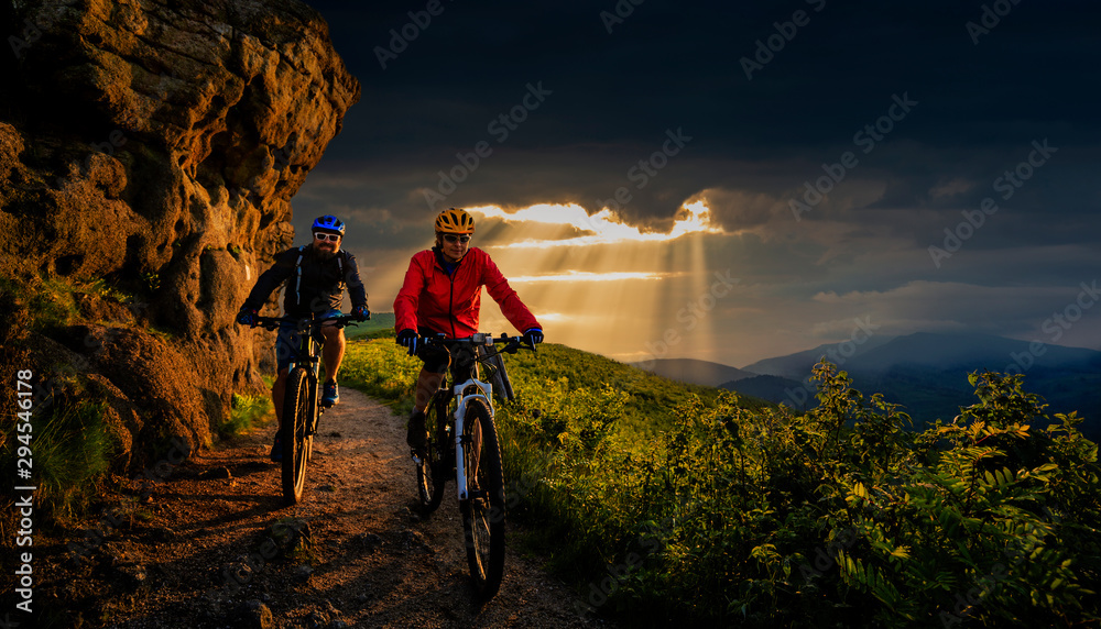 Fototapeta premium Cycling, mountain biker couple on cycle trail in autumn forest. Mountain biking in autumn landscape forest. Man and woman cycling MTB flow uphill trail.