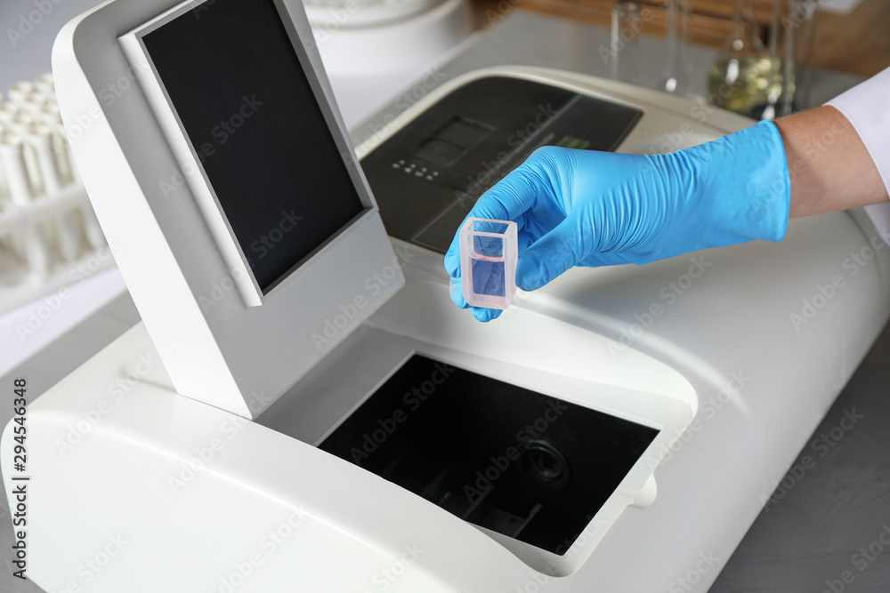 Scientist putting sample compartment with liquid in spectrophotometer, closeup. Laboratory analysis Scientist putting sample compartment with liquid in spectrophotometer, closeup. Laboratory analysis