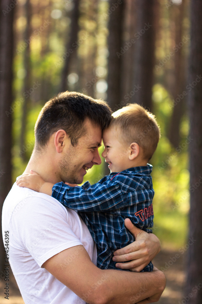 father and son walking along a path in the forest.Happy young father holding up in his arms little baby putting him up. Outdoor portrait. Happiness and harmonyFamily fun outside.