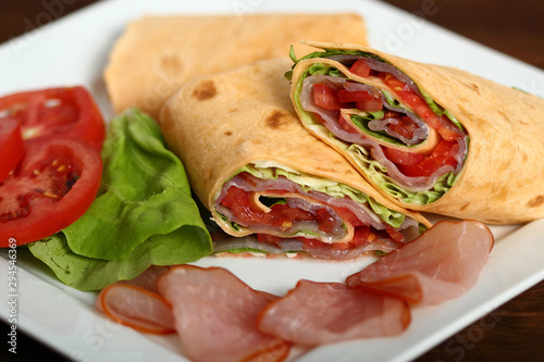 Wrap tortilla sandwich with ham, tomato, lettuce.