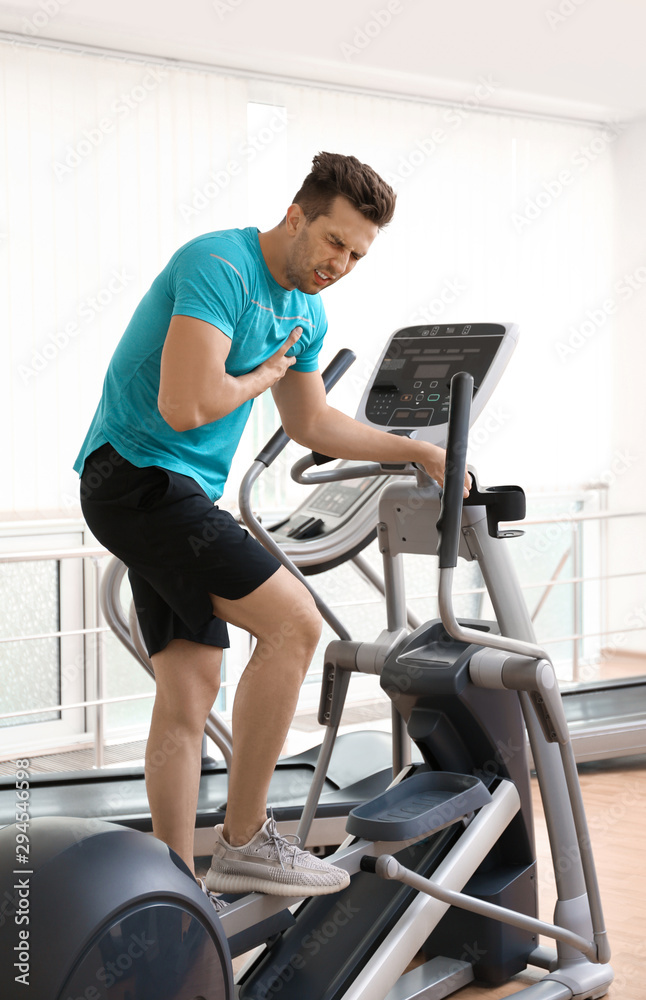 Young man having heart attack on treadmill in gym Young man having heart attack on treadmill in gym
