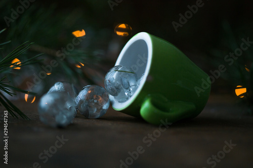 Coffee cup over Christmas lights bokeh in home on wooden table with tree. 