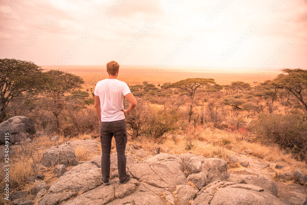 Fototapeta premium Man at view point looking to the bush savannah of Serengeti at sunset, Tanzania - Safari in Africa