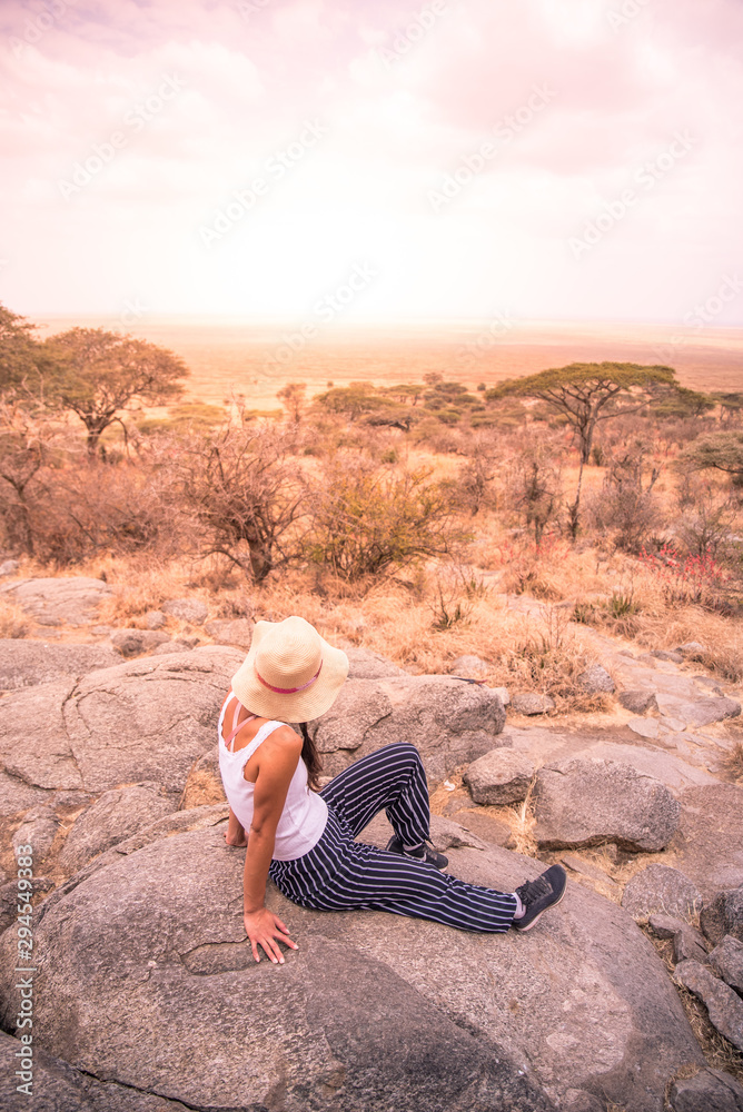 Girl at view point looking to the bush savannah of Serengeti at sunset, Tanzania - Safari in Africa