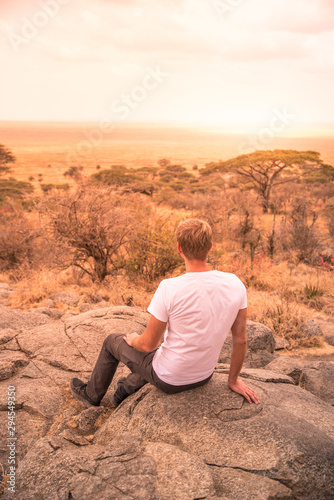 Man at view point looking to the bush savannah of Serengeti at sunset, Tanzania - Safari in Africa © Simon Dannhauer