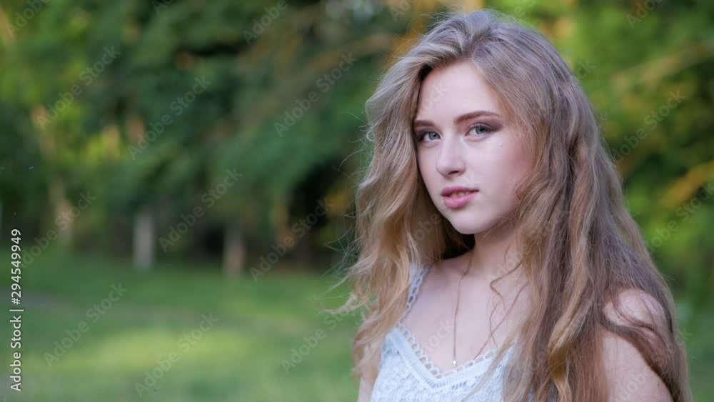 Portrait of a beautiful young girl with blond hair looking at camera. Slow motion. Portrait of a beautiful young girl with blond hair looking at camera. Slow motion.
