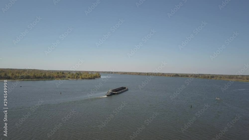 A tugboat ship pushes a barge upstream of the river to transport bulk materials. Aerial photography with a quadcopter or a drone. Panorama of the Dnieper - the main water transport artery of Ukraine A tugboat ship pushes a barge upstream of the river to transport bulk materials. Aerial photography with a quadcopter or a drone. Panorama of the Dnieper - the main water transport artery of Ukraine