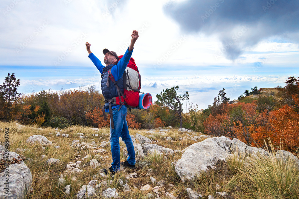 Traveler with a backpack stands on a high mountain with his hands up. Crimea Traveler with a backpack stands on a high mountain with his hands up. Crimea