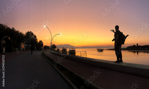 a photographer taking a photo with her cell phone on the lake at sunset time