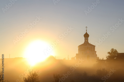 Beautiful golden autumn morning foggy sunny field and orthodox church 