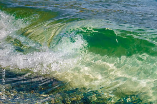 Wave of beautiful transparent emerald color on the coast on a bright sunny day 