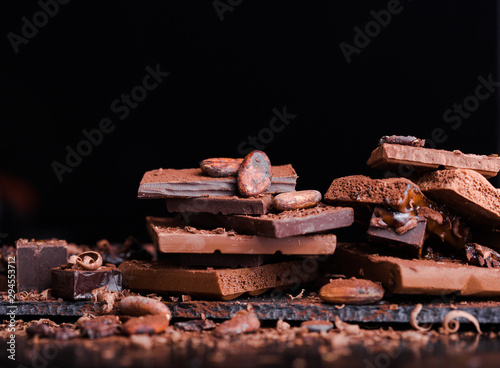 Assorted stack Chocolate Candies. Chocolate Sweets. Candy Design over dark brown Background. Various Chocolates. Confectionery