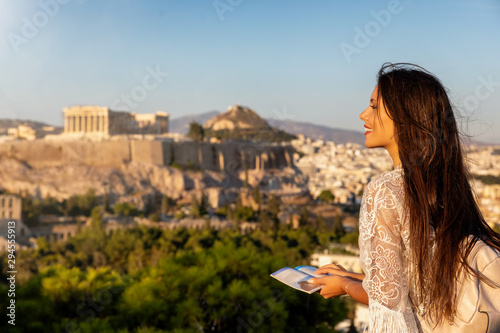 Fototapeta Naklejka Na Ścianę i Meble -  Touristin mit Reiseführer in der Hand schaut auf den Parthenon Tempel der Akropolis von Athen, Griechenland, bei Sonnenuntergang im Sommer