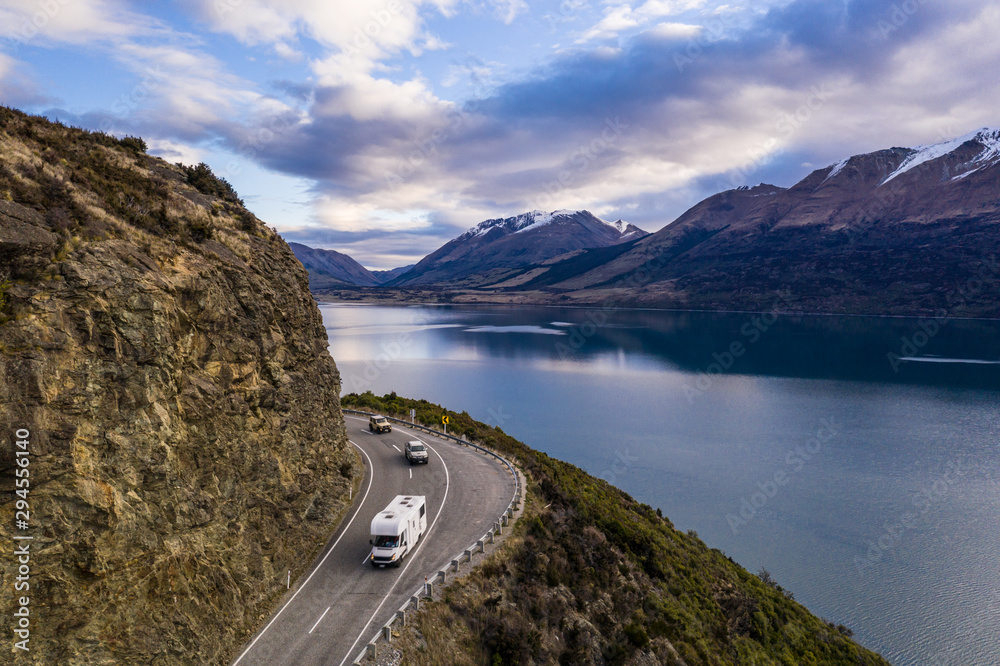 Camping car driving along the stunning lake Wakapitu between Queenstown and Glenorchy in New Zealand south island at sunset - obrazy, fototapety, plakaty 