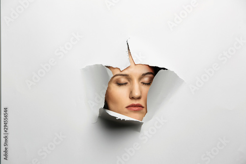 Woman looking out from a hole of torn paper
