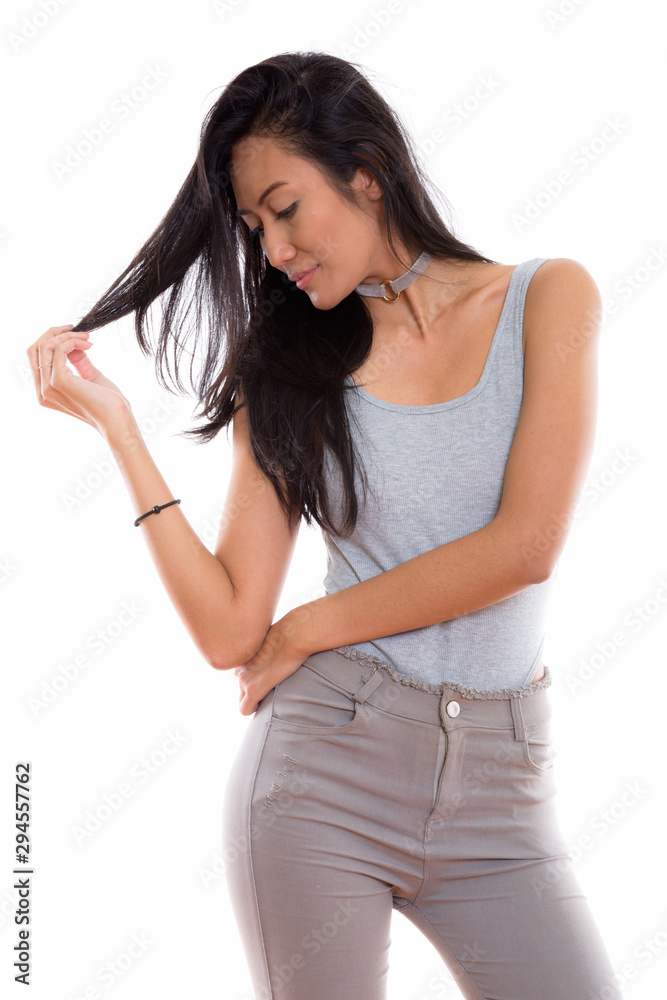 Studio shot of young beautiful Asian woman touching while lookin Studio shot of young beautiful Asian woman touching while lookin