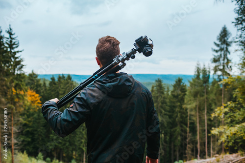 Photographer looks on a nice landscape with camera and tripod