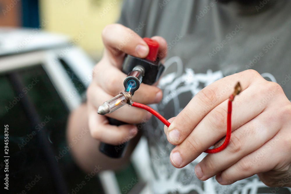 Repair wires. A man checks the wires with a tool. Spare part in the car. Hands of the master at work.