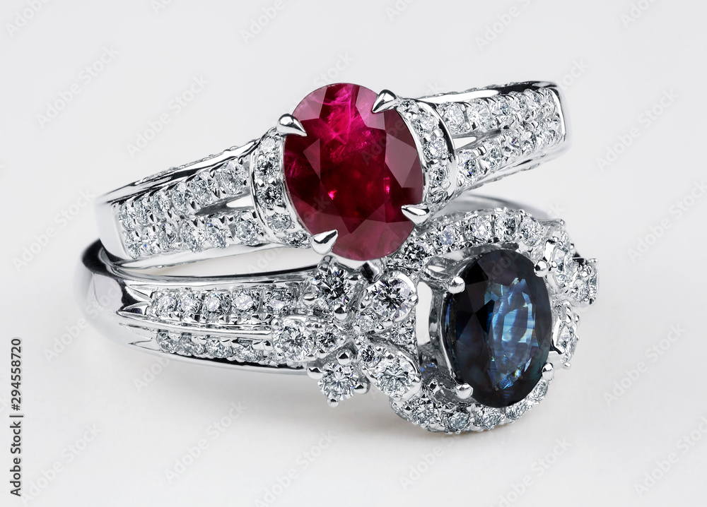 Diamond rings. Diamond rings with sapphire and ruby on white background. Rings with diamonds and large sapphire. Golden wedding rings. White gold.