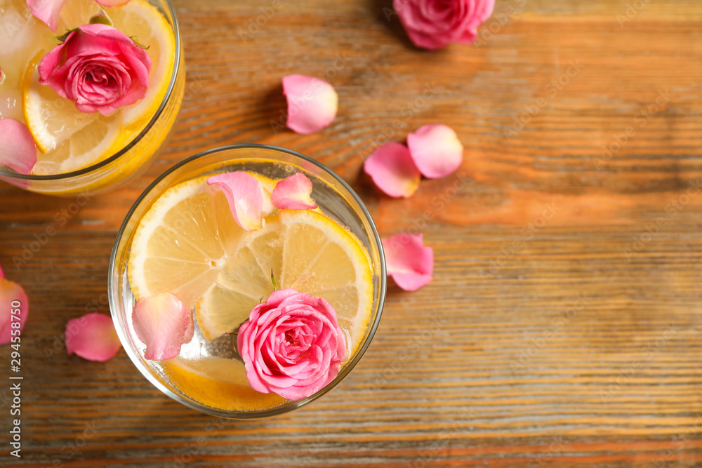 Tasty refreshing lemon drink with roses on wooden table, flat lay Tasty refreshing lemon drink with roses on wooden table, flat lay