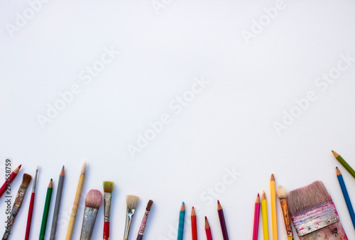 some brushes and colored pencils on a white paper 白い紙の上に絵筆と色鉛筆いろいろ