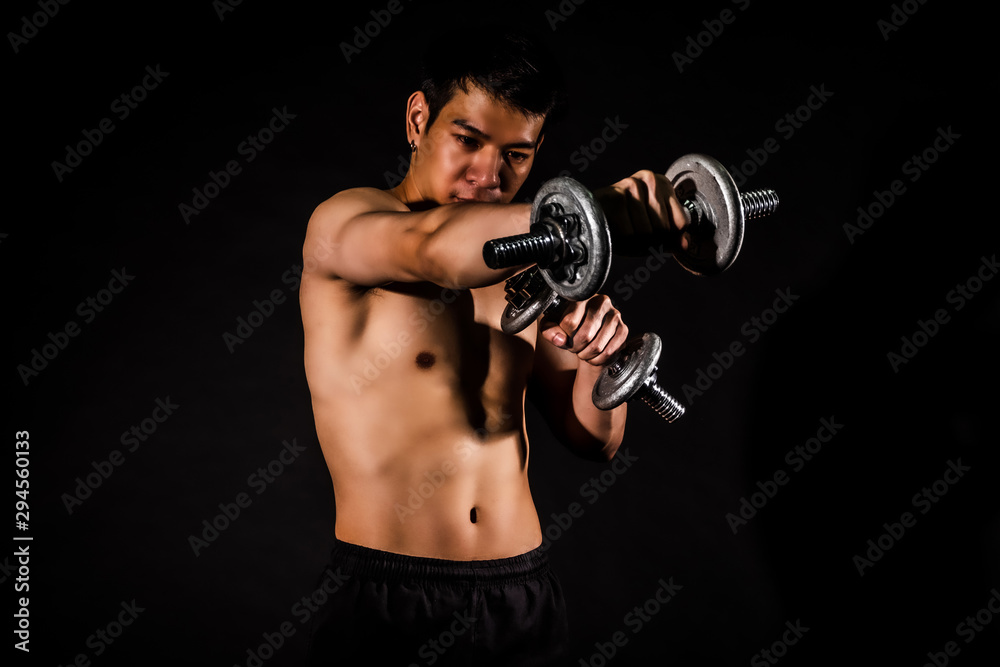 sport man standing doing exercise for arms with dumbbells and showing muscle bodybuilding on black backgrounds, fitness concept, sport concept