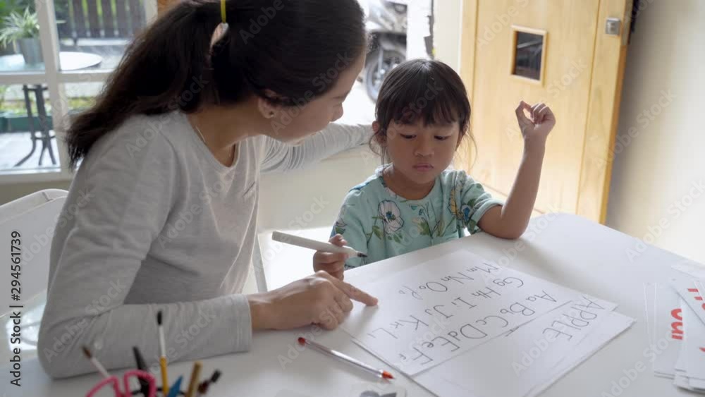 happy mother teaching her daughter the basic to read and write at home. toddler kindergarten student