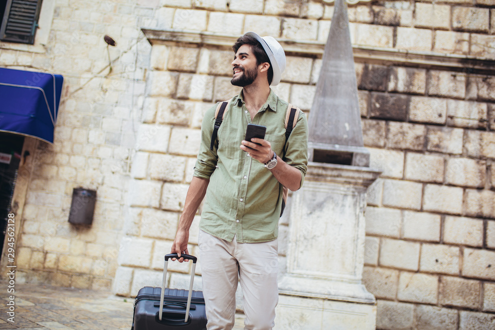 Handsome bearded tourist with backpack is making travel across city.
