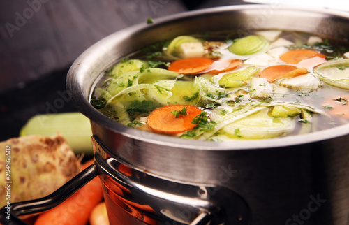 Broth with carrots, onions various fresh vegetables in a pot - colorful fresh clear spring soup. Rural kitchen scenery vegetarian broth photo