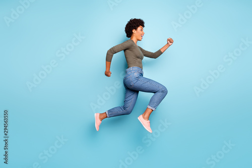 Full length body size photo of cheerful charming cute jumping fast quick woman running towards shopping mall for sales wearing jeans denim isolated over vivid color blue background