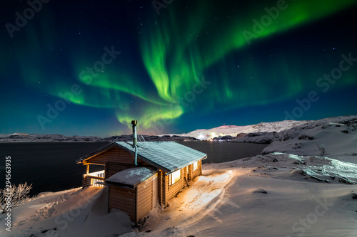 фотографія Wooden cottage on the background of the Northern Lights at night.