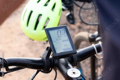 Close-up view of the electronic device of an electric bike. Yellow helmet on background