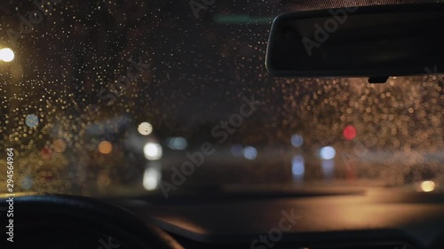 Beautiful background of front car window in raindrops cleaning by windscreen wiper at late night