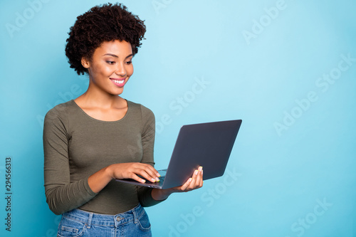 Photo of cheerful creative cute nice freelance worker wearing jeans denim holding electronic device with her hands laptop working with technology isolated over vivid color blue background