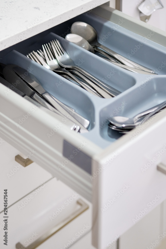 Open kitchen table drawer where stacked compartments forks spoons accessories, close up view no people Open kitchen table drawer where stacked compartments forks spoons accessories, close up view no people