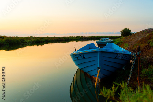 abandoned blue fishing boat at dawn in ebro delta park in catalunya, a quiet scene with warm colors symbol of loneliness and peace of mind photo