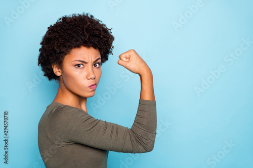 Photo of black millennial girl showing you her biceps thinking on result boasting about her strength isolated over vivid color background photo