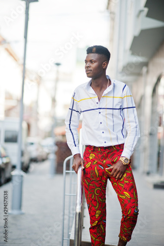 Portrait of handsome stylish african american model man in red throusers and white shirt. photo